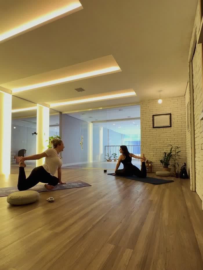 Camille orientando uma aluna durante uma prática de yoga